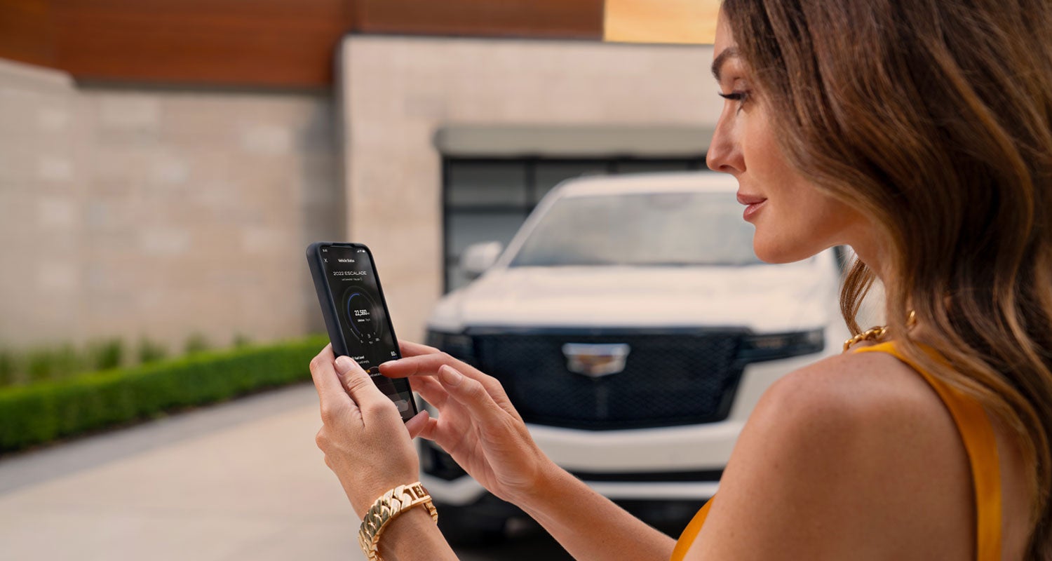 lady checking her mobile with a Cadillac vehicle background | Coughlin Cadillac Circleville in Circleville OH